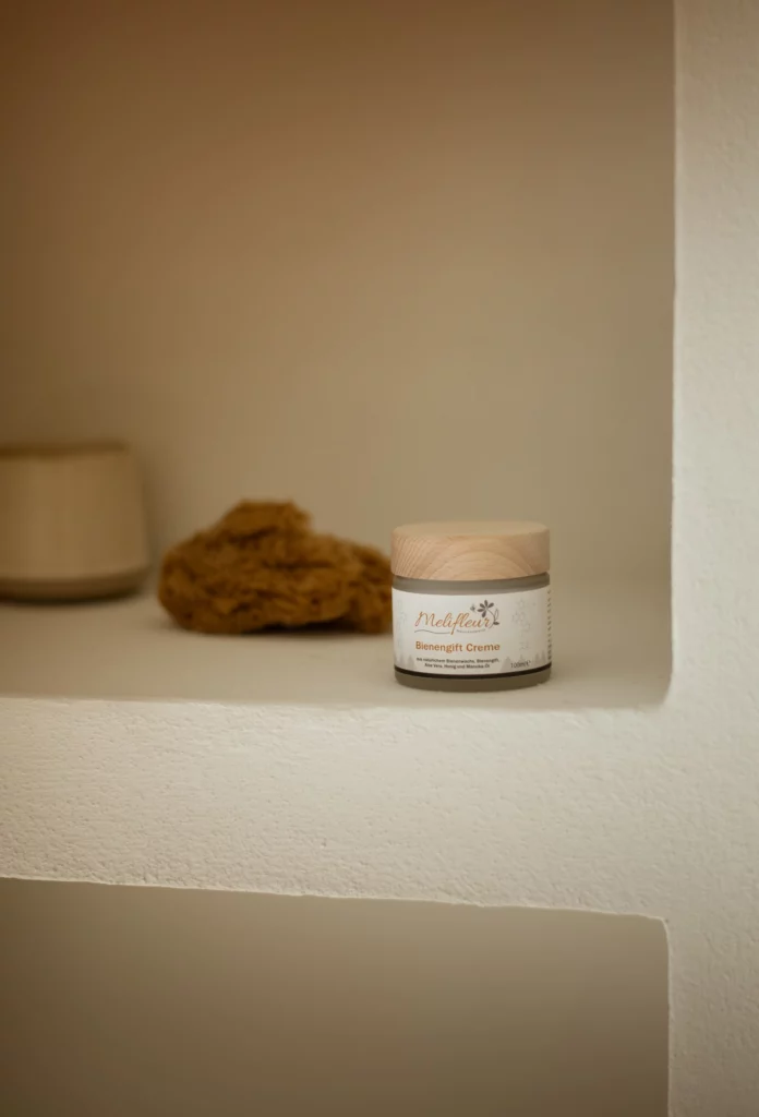 Ein Tiegel Medjex Beemart Creme steht auf einem weißen Regal neben einem Naturschwamm und einem kleinen Behälter.