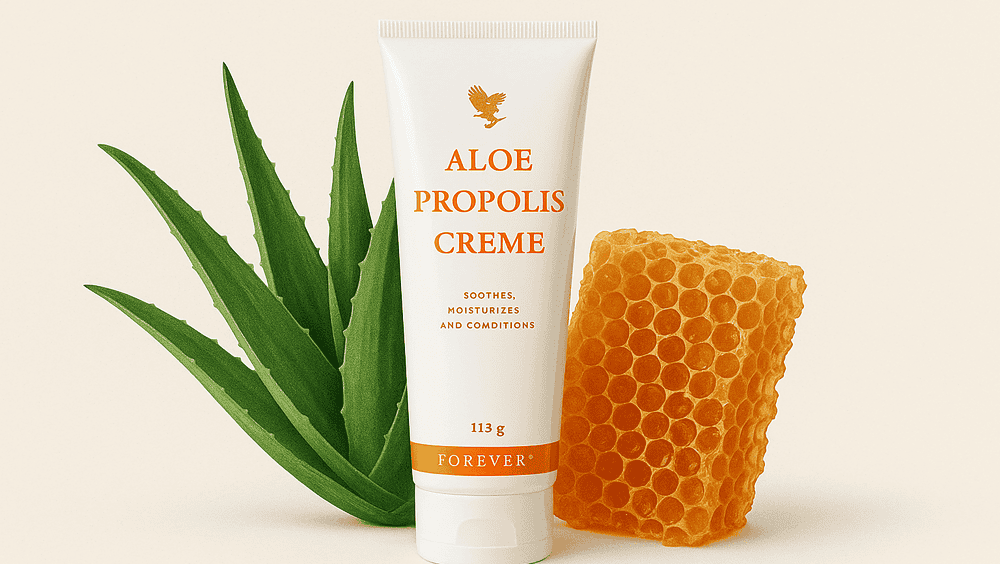 Eine Tube Aloe Propolis Creme steht aufrecht zwischen einem Aloe-Vera-Blatt und einer Honigwabe vor einem hellen Hintergrund.